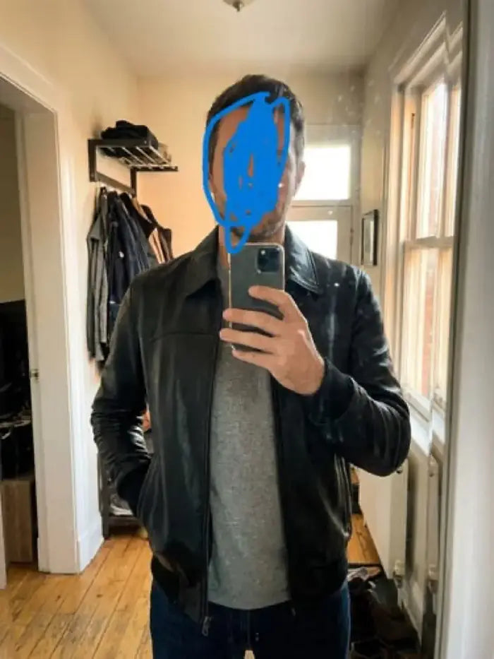 Verified client Elena Rostova (Munich, DE) wearing the Orlaven Mens Shirt Collar Black Bomber Leather Jacket in deep onyx black 100% full-grain leather, showcasing tailored shoulder seams, heavy brass hardware, and rich natural leather patina in Munich.