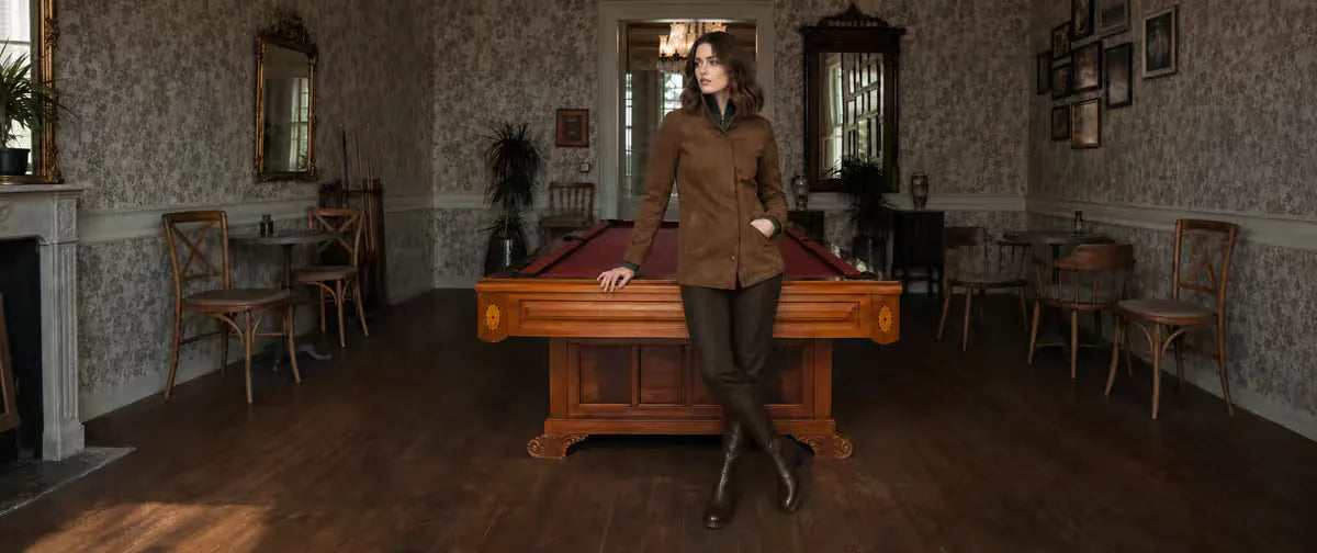 Woman wearing a brown ORLAVEN suede jacket beside a billiards table